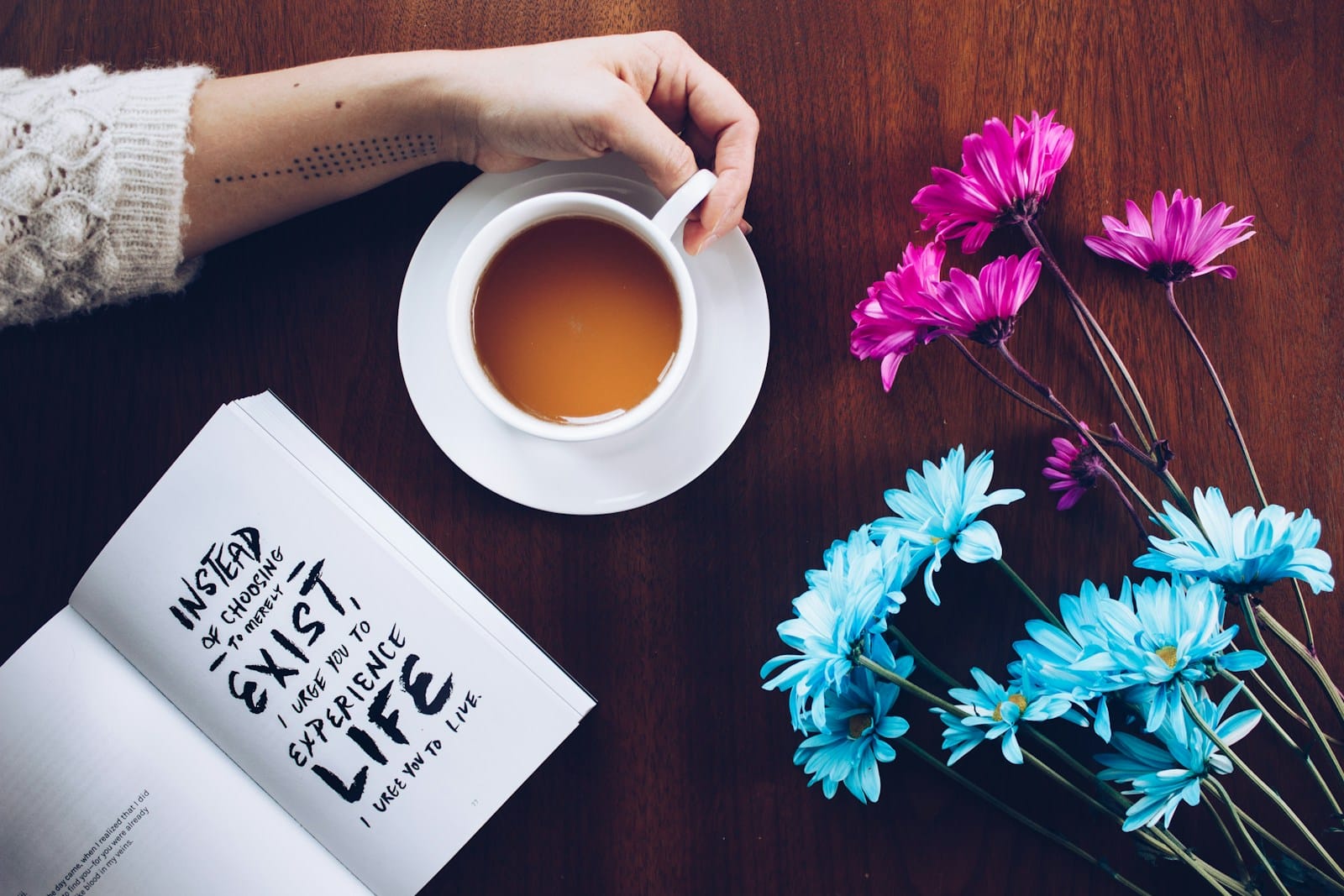 Photo by Thought Catalog person holding mug beside flowers