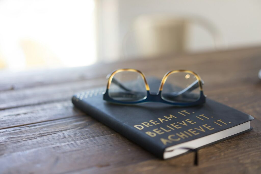 Photo by carolyn christine black and brown eyeglasses on book on brown wooden table